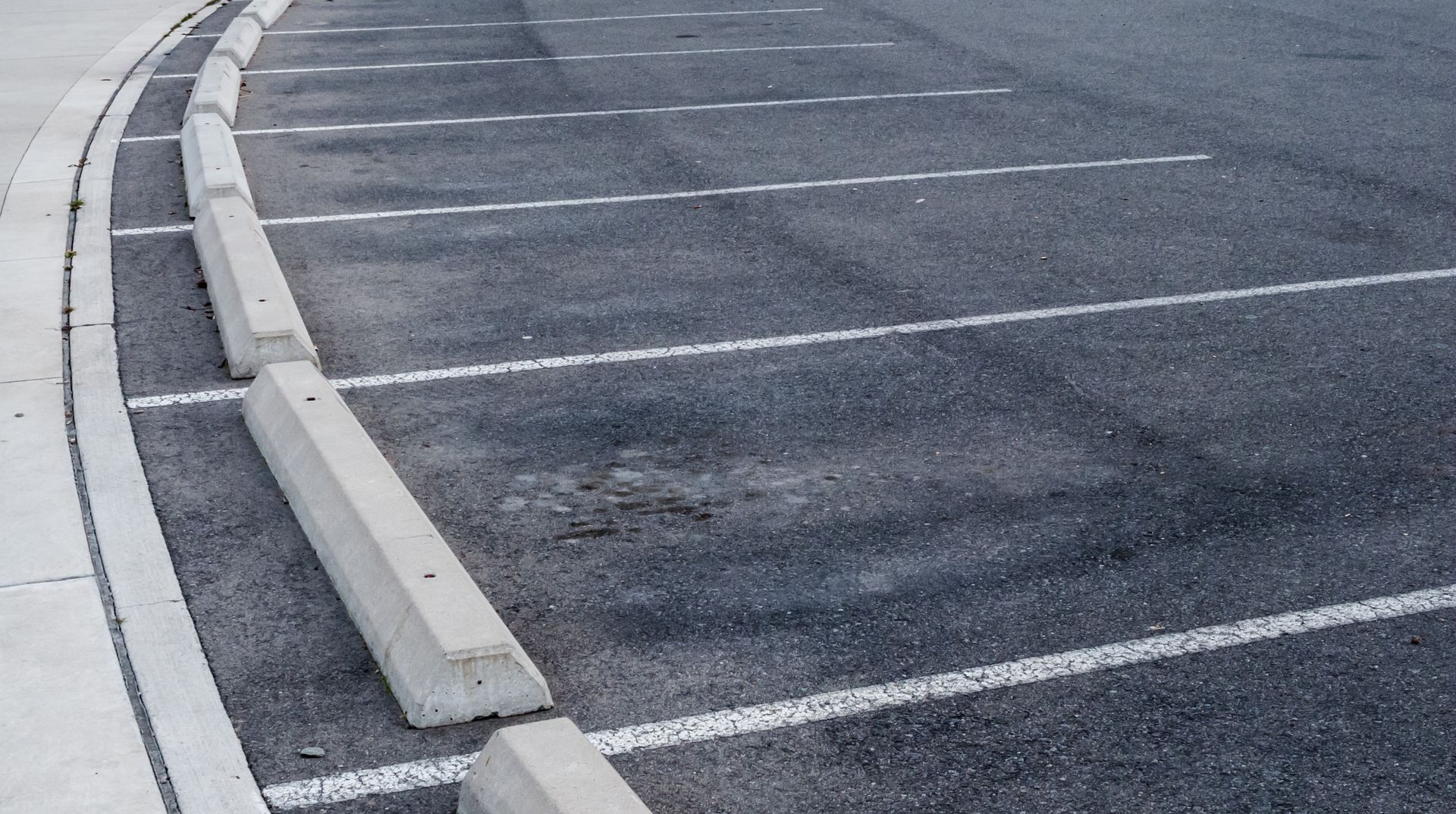 A row of parking spaces with concrete curbs on the side of the road.