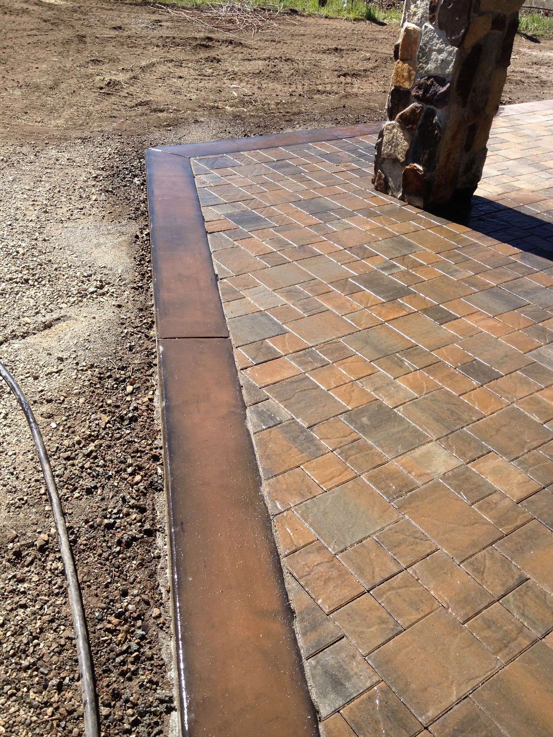 A brick walkway with a stone pillar in the background.