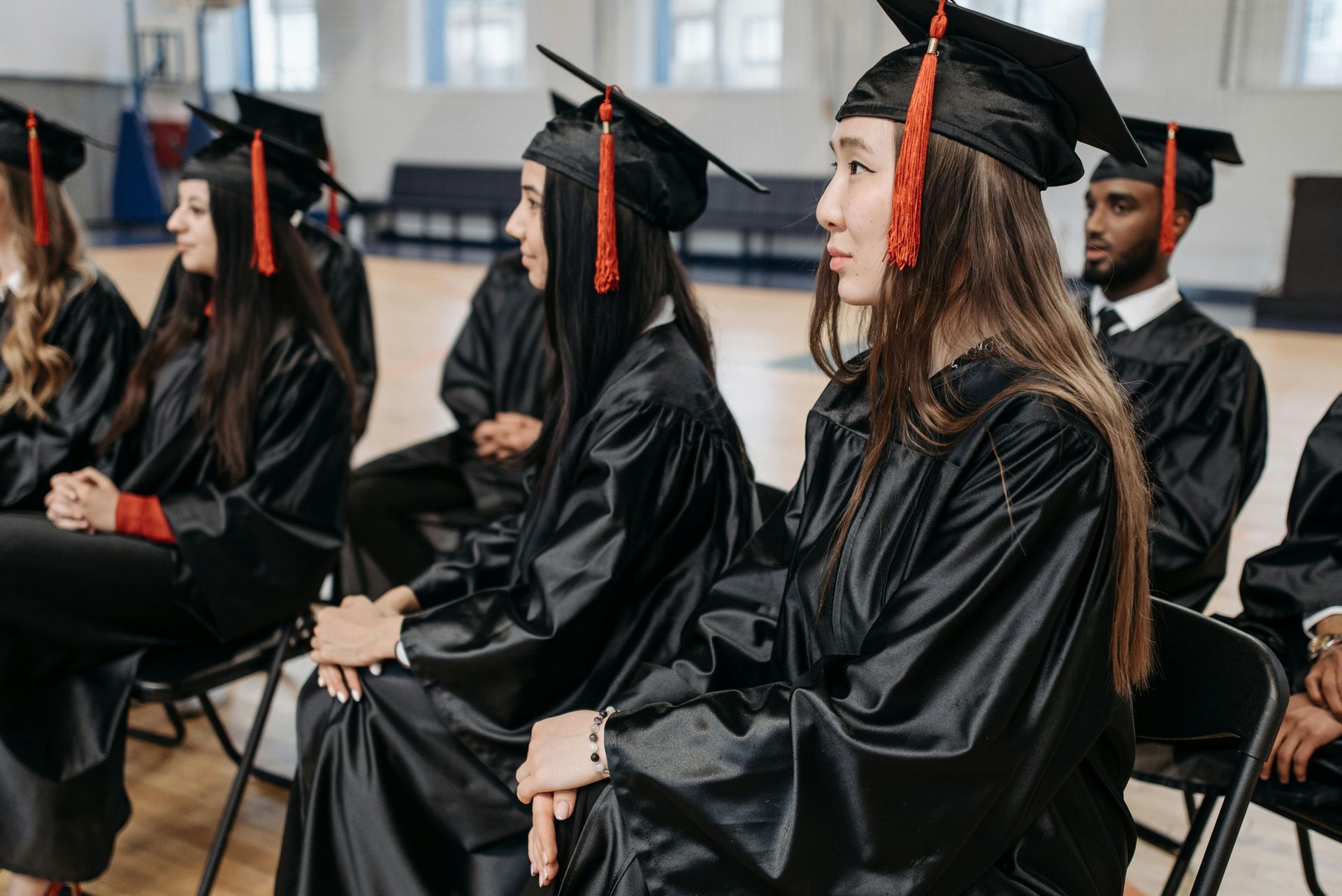 Graduates in black caps and gowns seated at a commencement ceremony