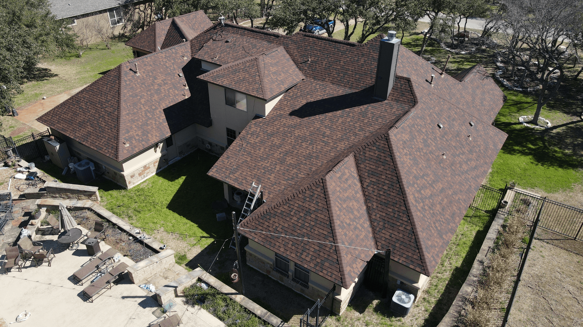 Aerial view of a large brown-roofed house surrounded by green grass and trees — C&A Roofing in Boambee East, NSW