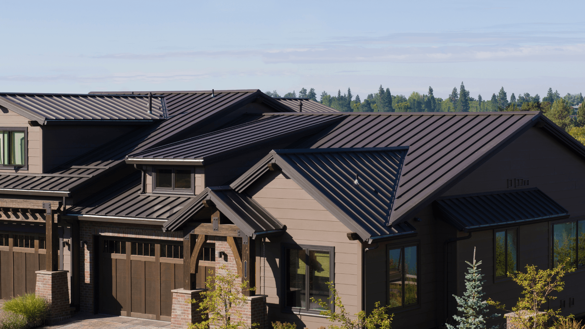 Brown house with black metal roof, set against a backdrop of trees and a blue sky — C&A Roofing In Boambee East, NSW