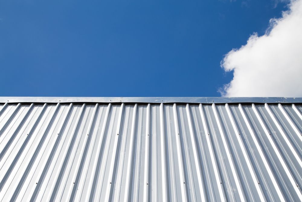 Silver corrugated metal roof against a bright blue sky with a white cloud — C&A Roofing In Taree, NSW