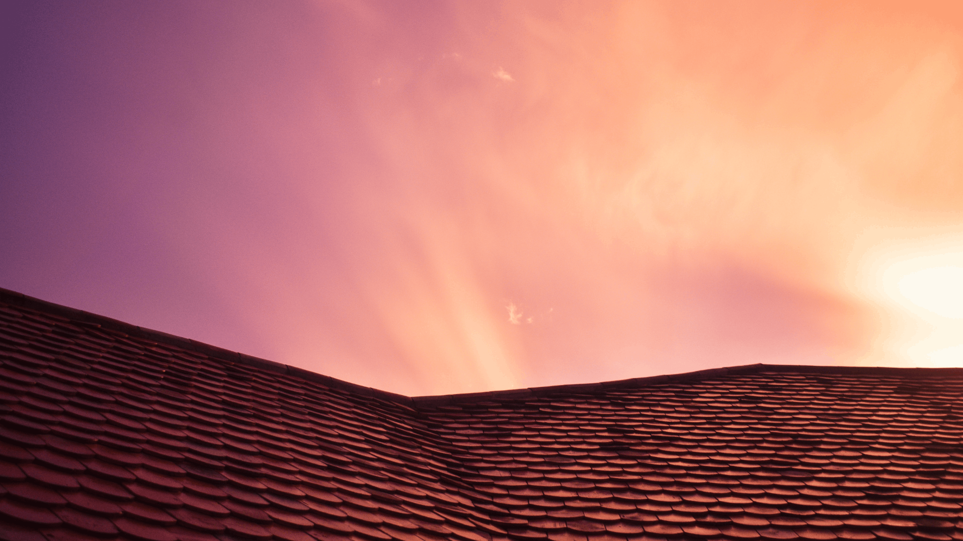 Rooftop silhouetted against a vibrant purple and orange sunset sky — C&A Roofing In Taree, NSW