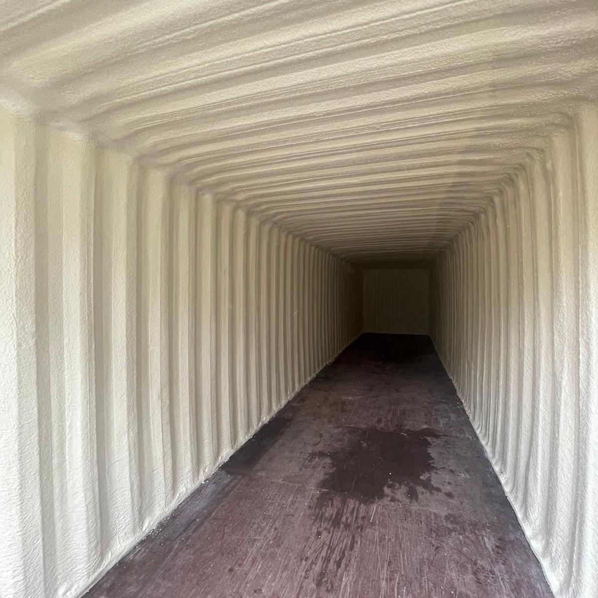 An empty shipping container with a wooden floor and white walls.