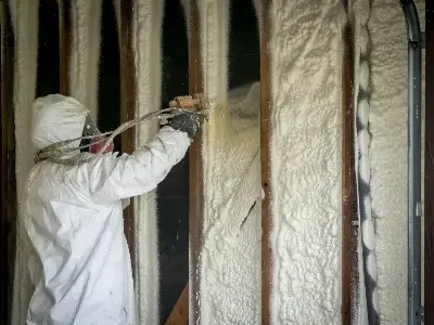 A man is spraying foam on a wall.
