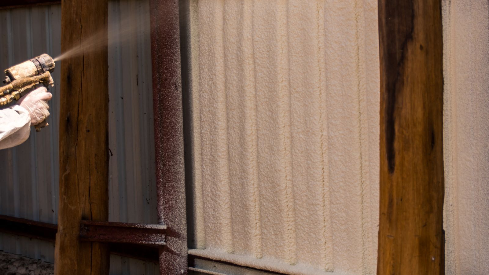 A person is spraying paint on a wooden post.