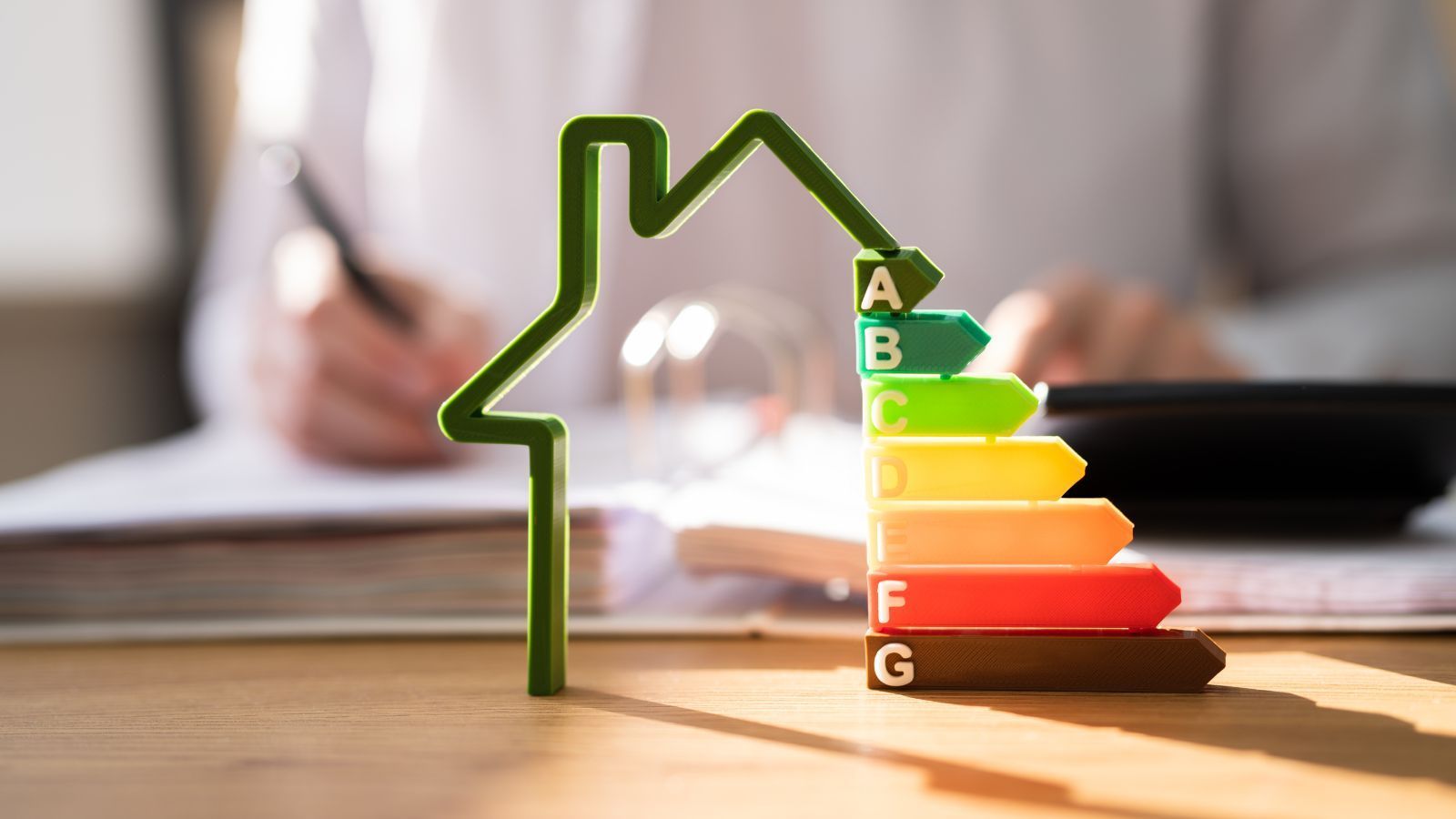 A person is sitting at a table with a calculator and a green house.