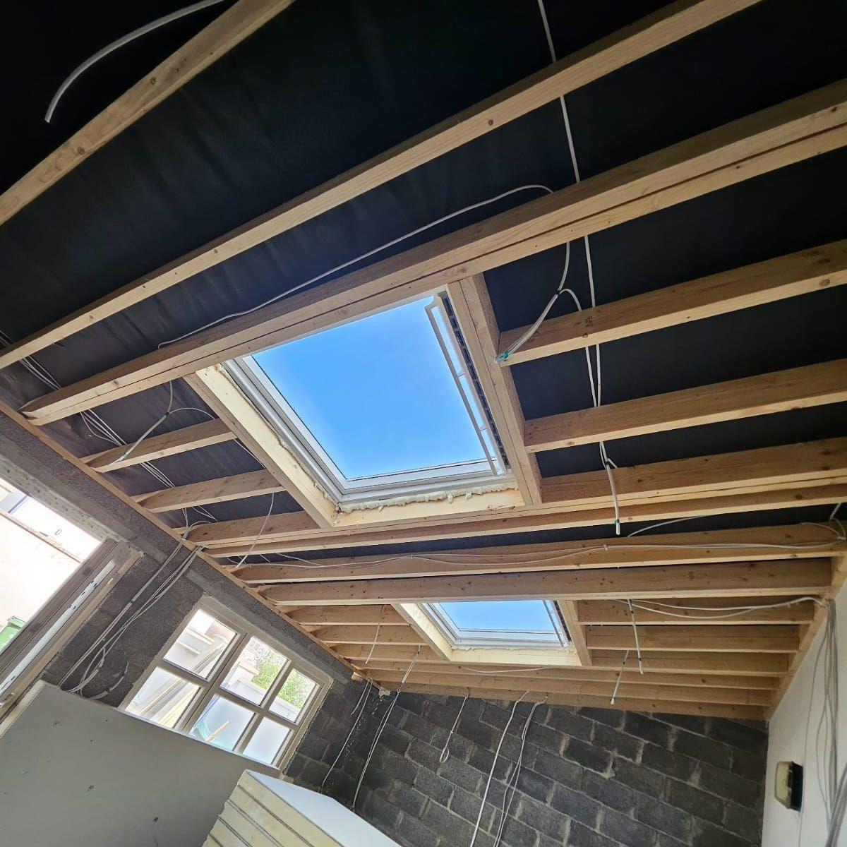 A room under construction with a skylight in the ceiling.