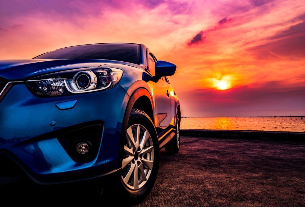A Blue Car Is Parked On The Beach At Sunset — Manning Smash & Auto Repairs In Wingham, NSW