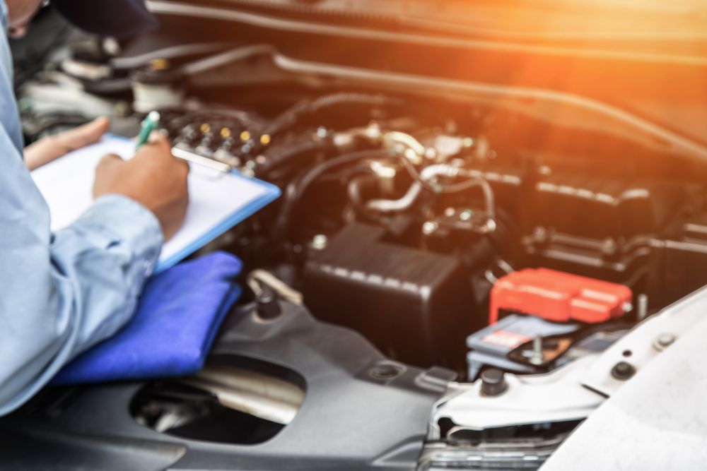 Mechanic Is Writing On A Clipboard While Looking Under The Hood Of A Car — Manning Smash & Auto Repairs In Wingham, NSW