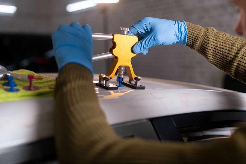 A Person Is Using A Tool To Fix A Roof Of A Car — Manning Smash & Auto Repairs In Wingham, NSW