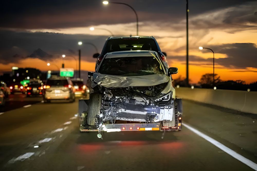 A Damaged Car Is Driving Down A Highway At Night — Manning Smash & Auto Repairs In Wingham, NSW