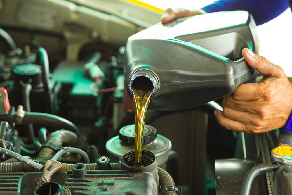 A Person Is Pouring Oil Into A Car Engine — Manning Smash & Auto Repairs In Wingham, NSW