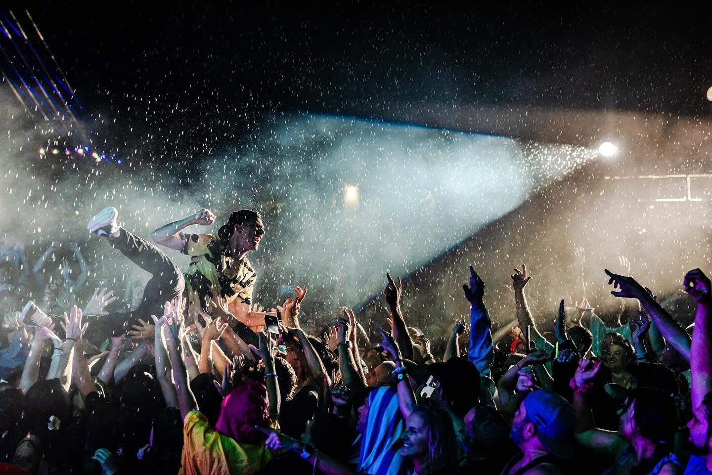 A group of people are standing in front of a stage at a concert.