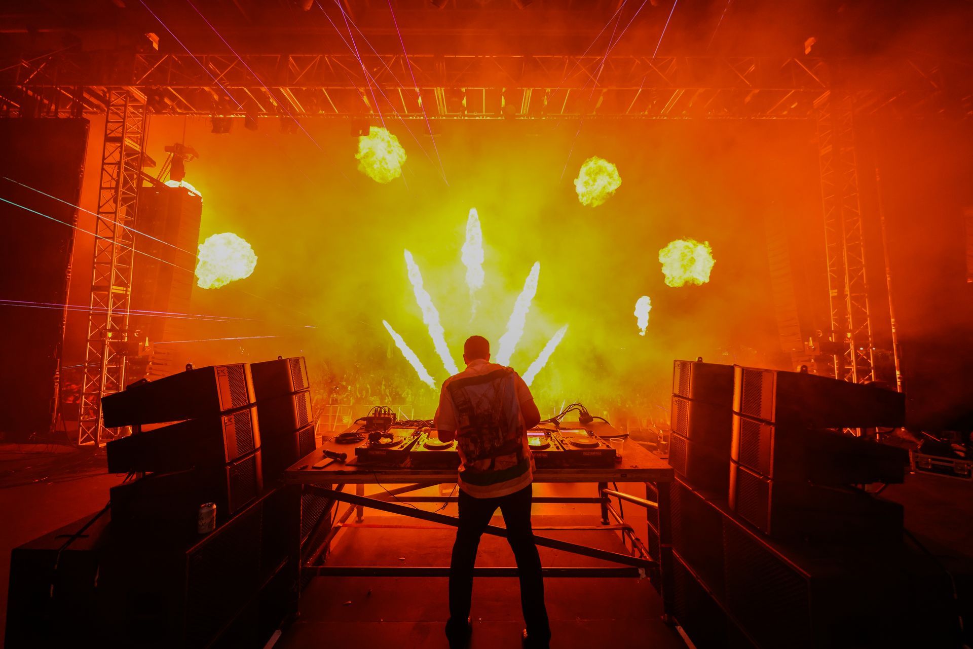 A man is standing on a stage playing a dj set.