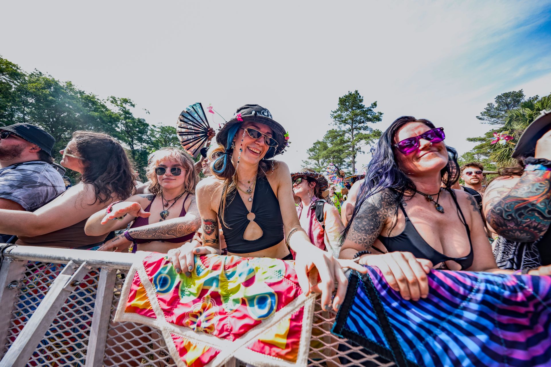 A group of people are standing behind a fence at a music festival.