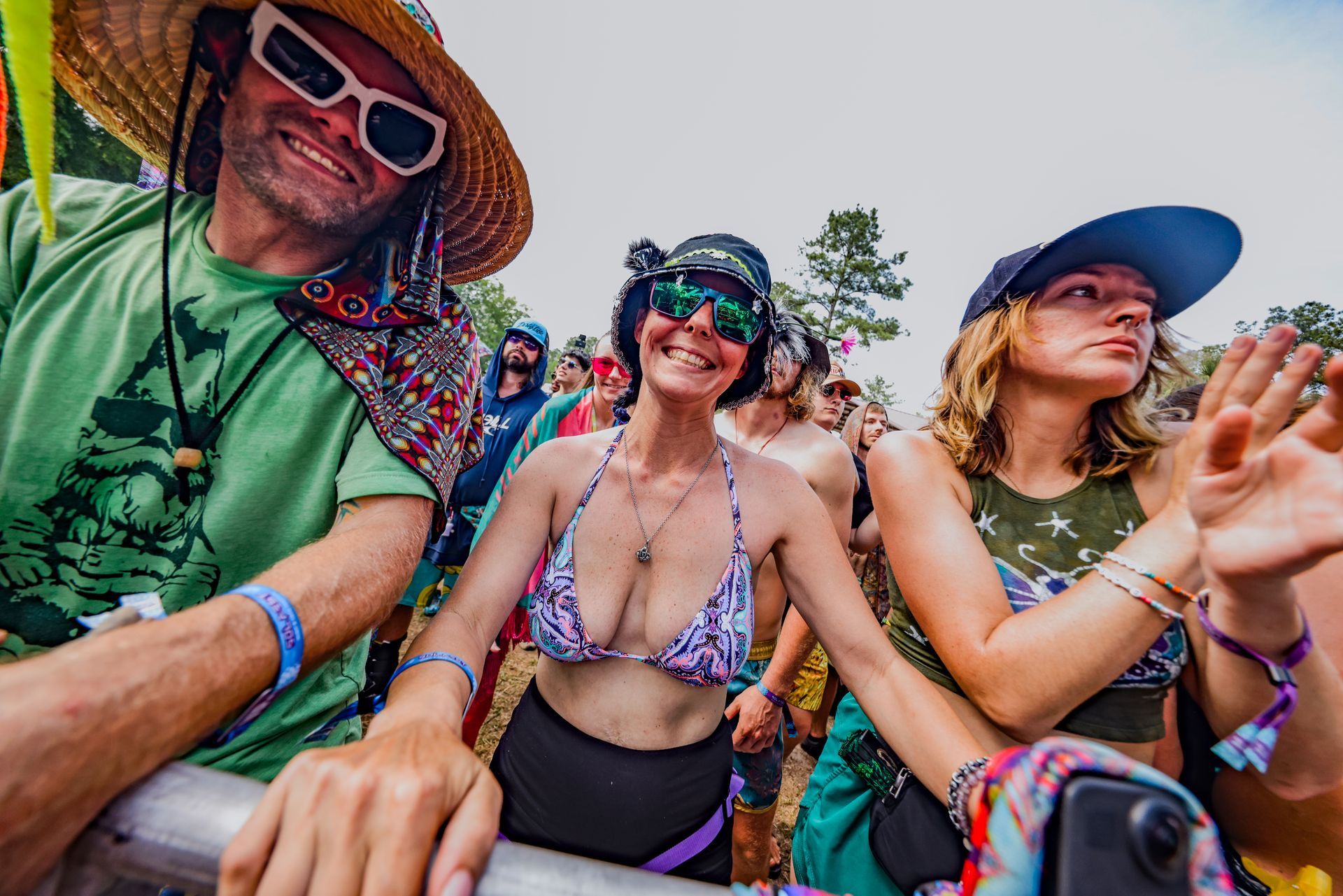 A group of people are sitting on a fence at a festival.