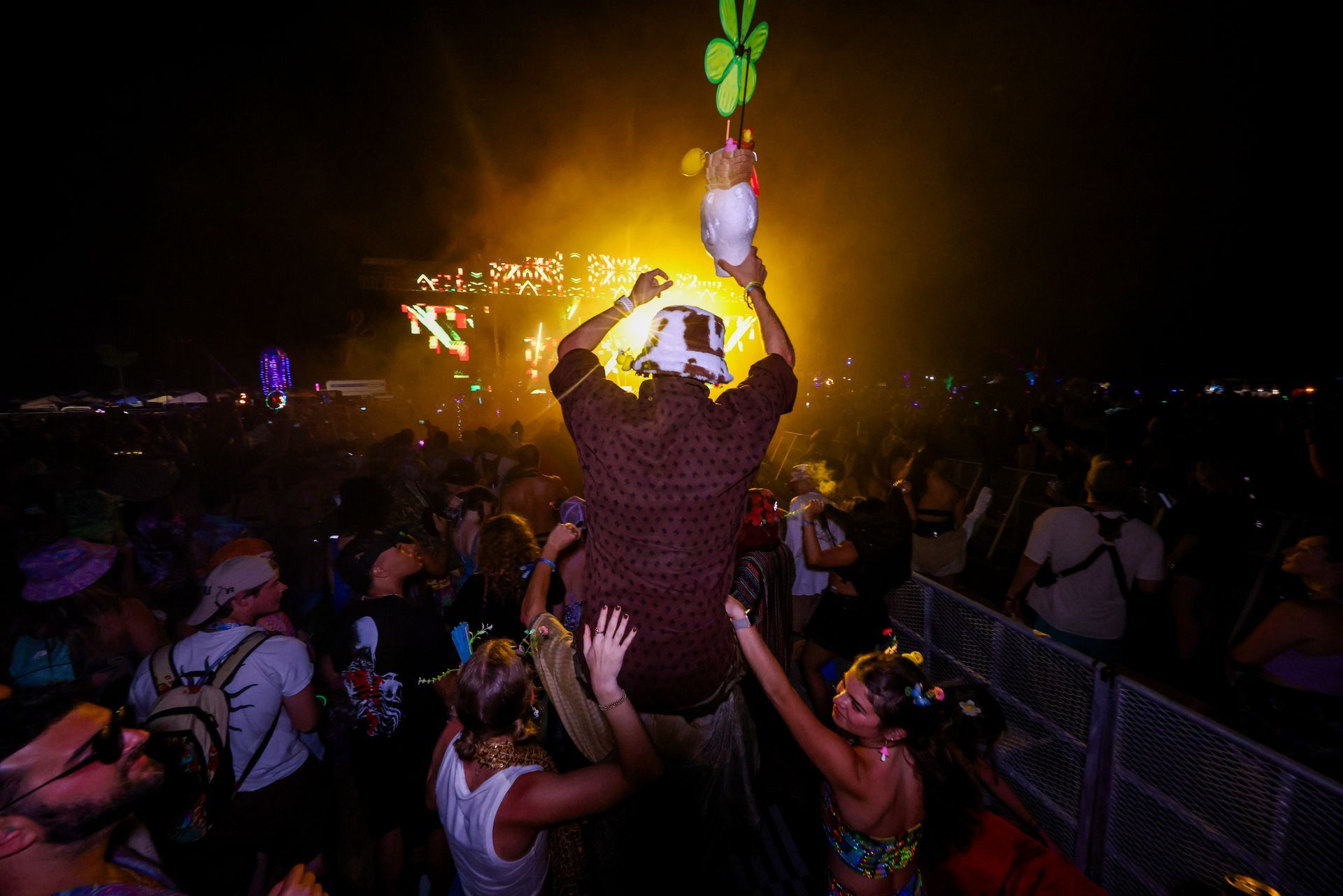 A crowd of people are dancing at a music festival at night.