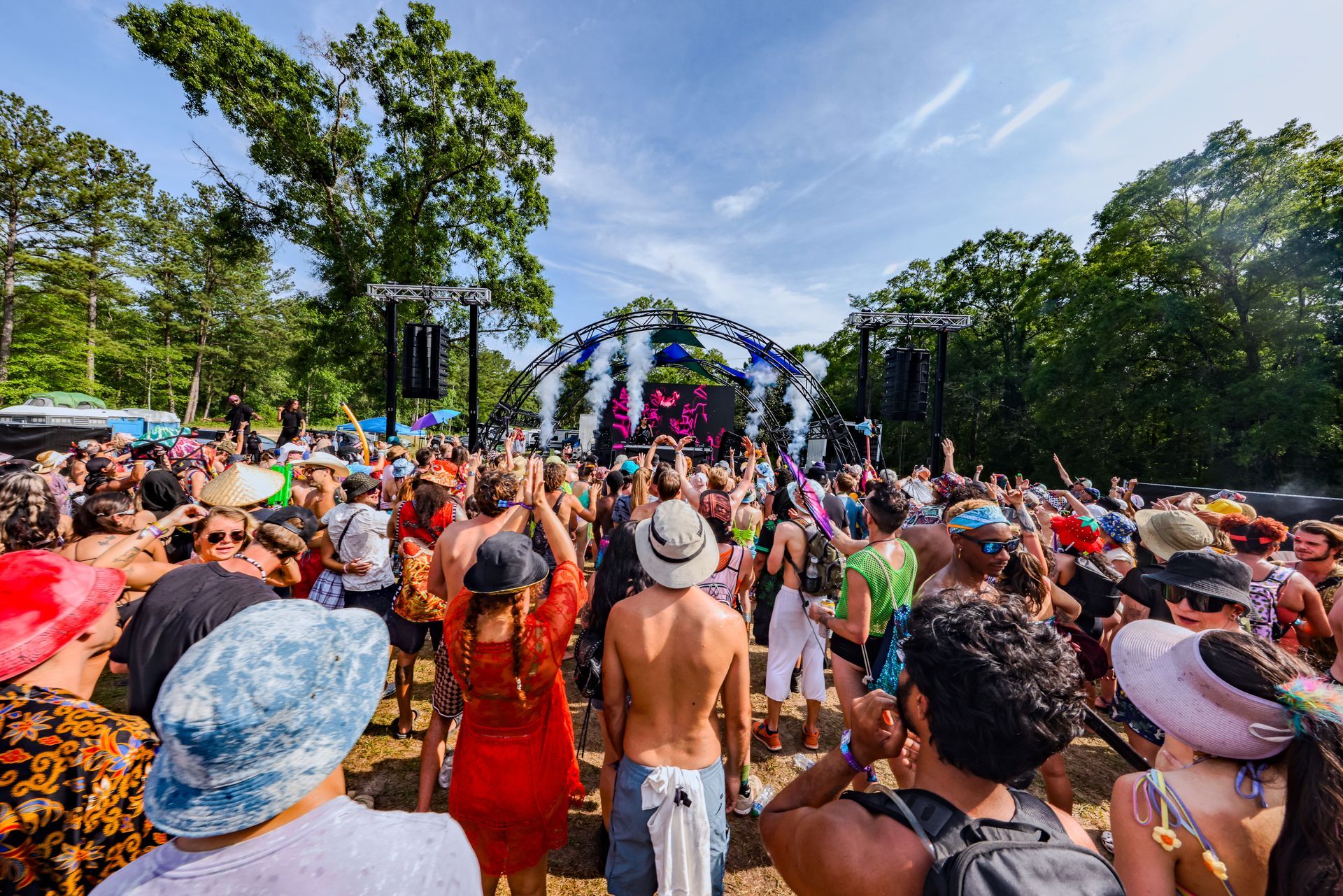 A crowd of people are standing in front of a stage at a music festival.