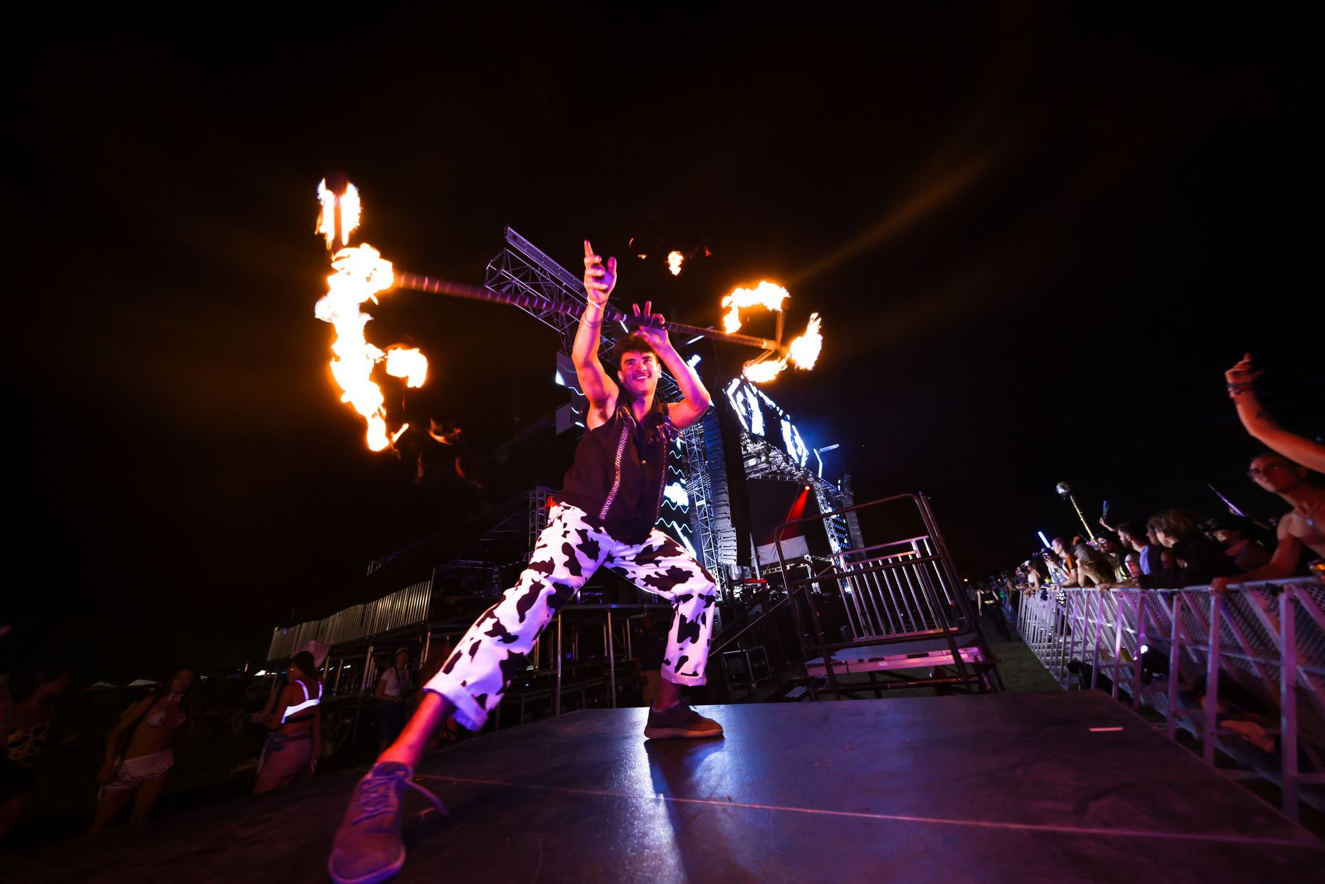 A man is holding a torch with flames coming out of it while standing on a stage.