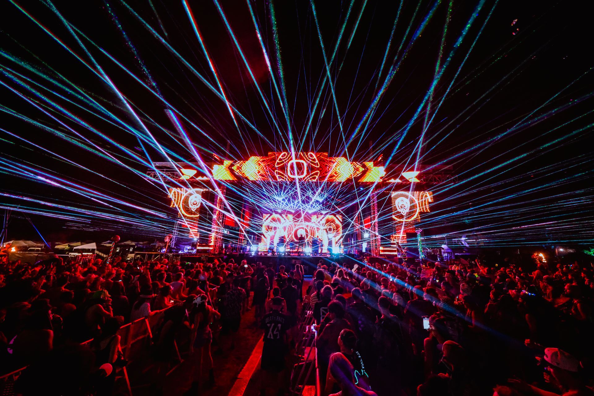 A crowd of people are standing in front of a stage at a concert.