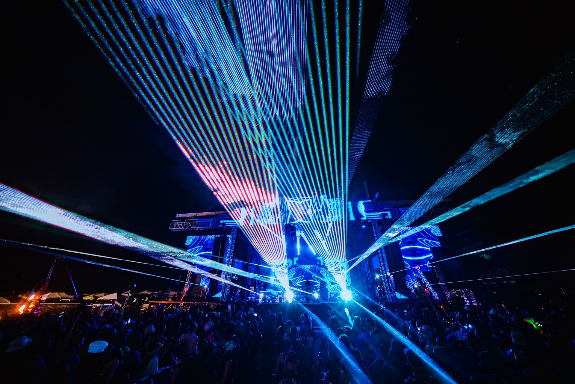 A crowd of people are watching a laser show at a concert.