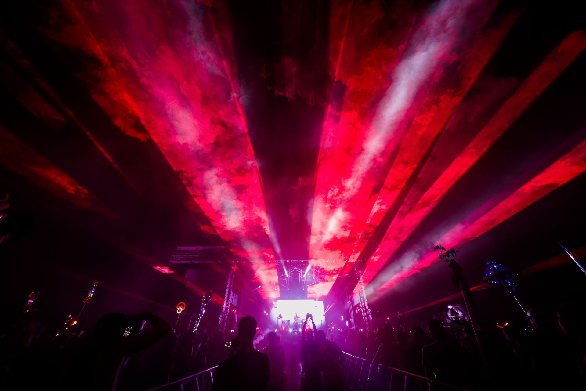 A crowd of people are standing in front of a stage with red lights coming out of it.