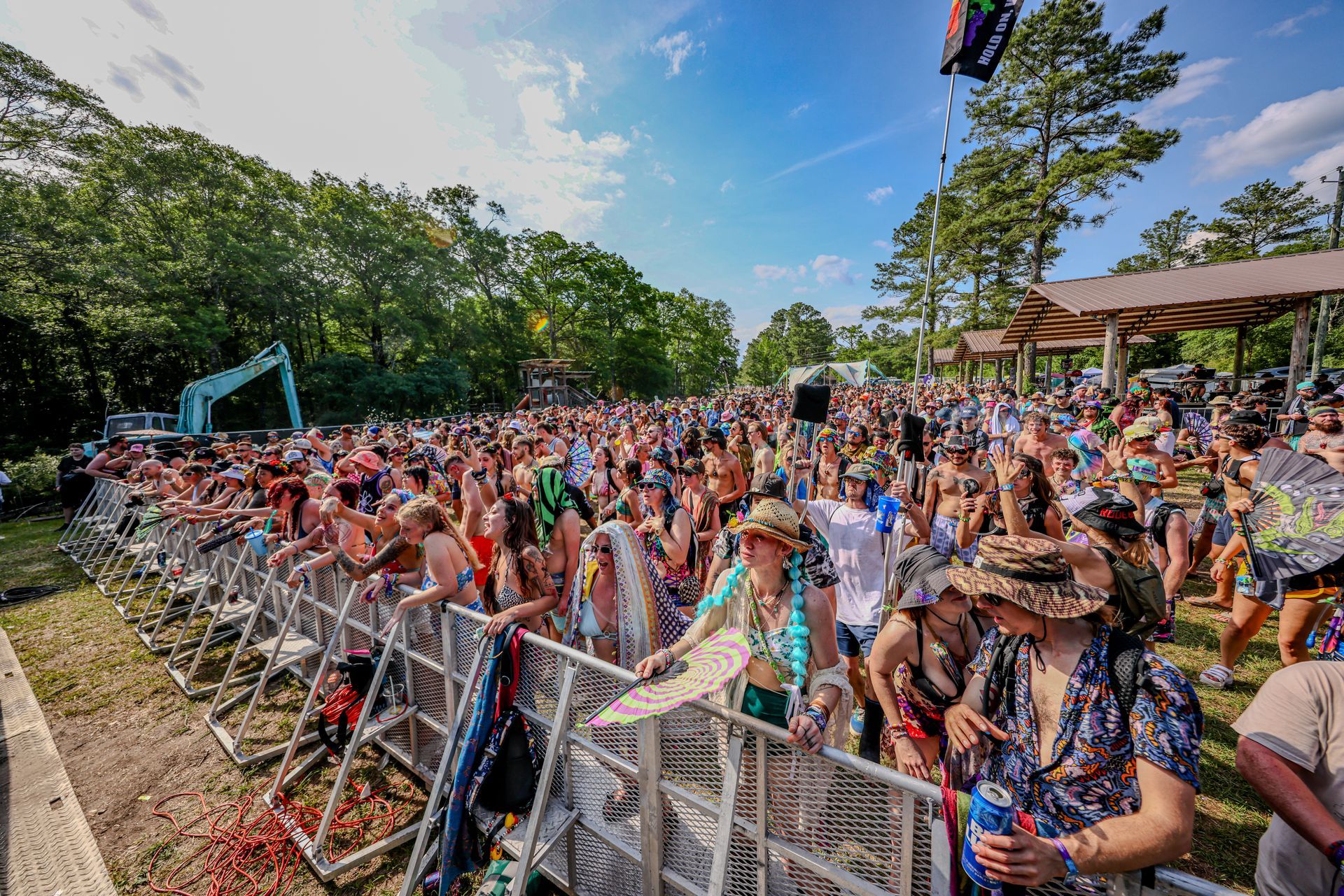 A large crowd of people are standing in front of a fence at a music festival.