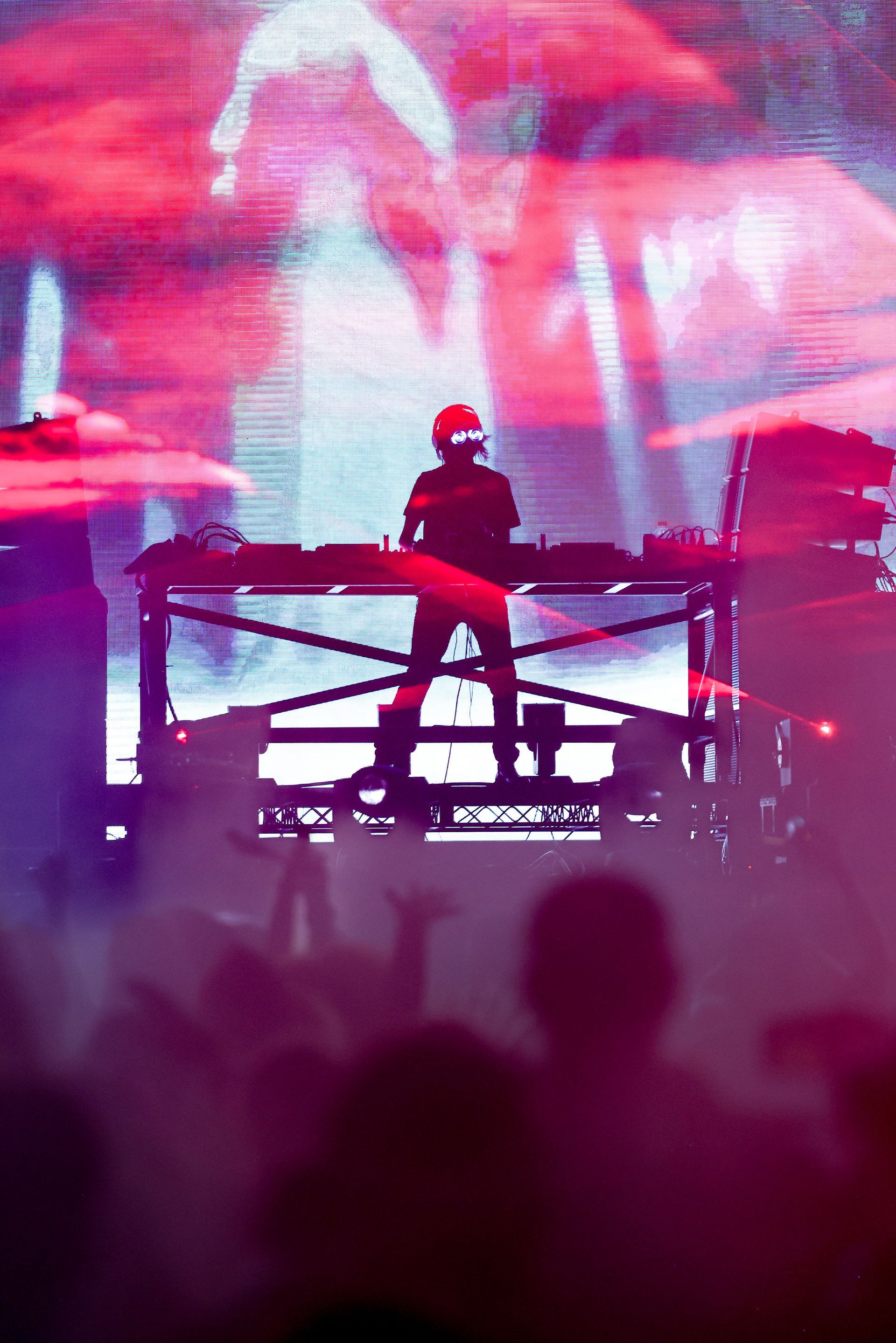 A dj is playing music on a stage in front of a crowd.