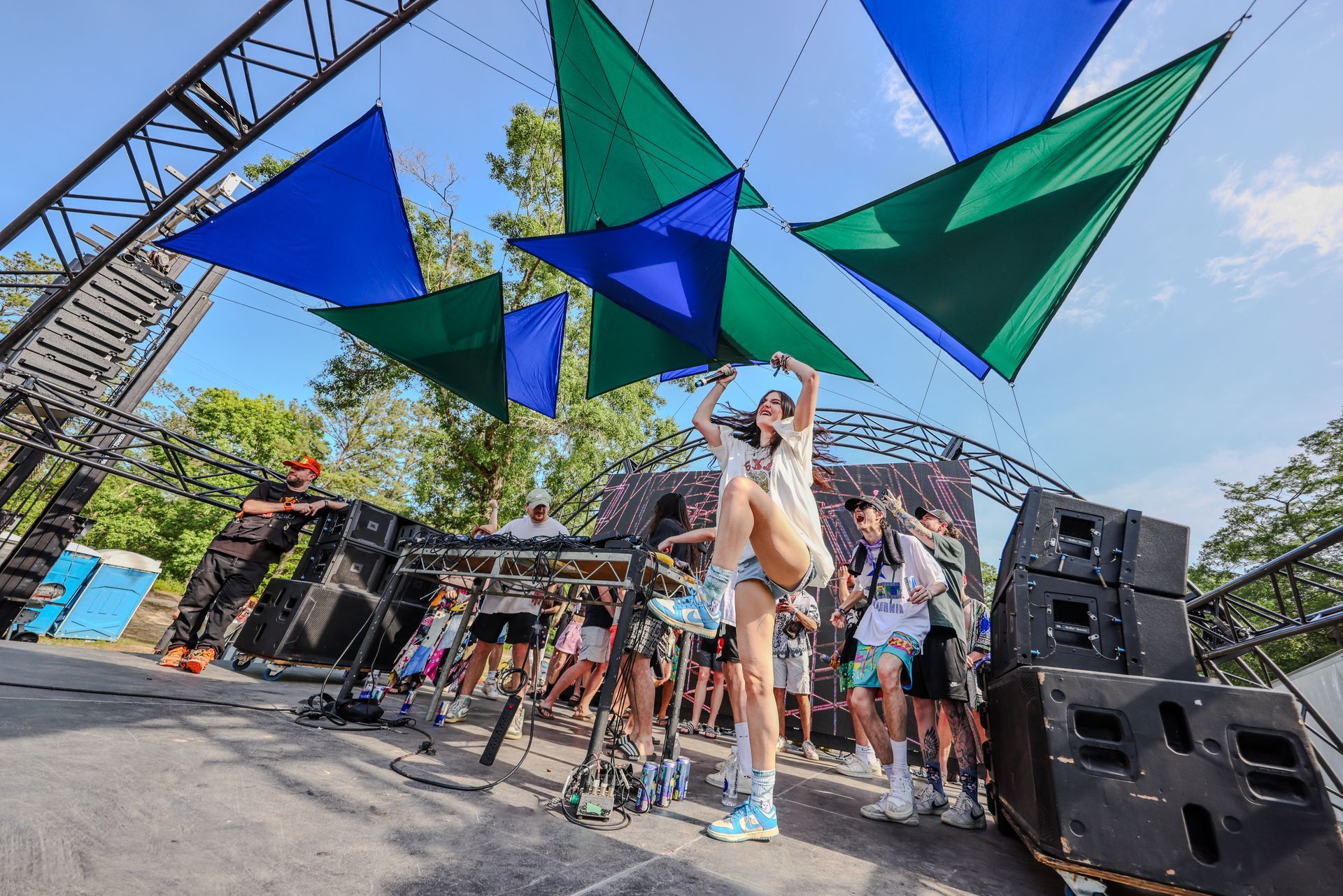 A group of people are standing in front of a stage at a music festival.