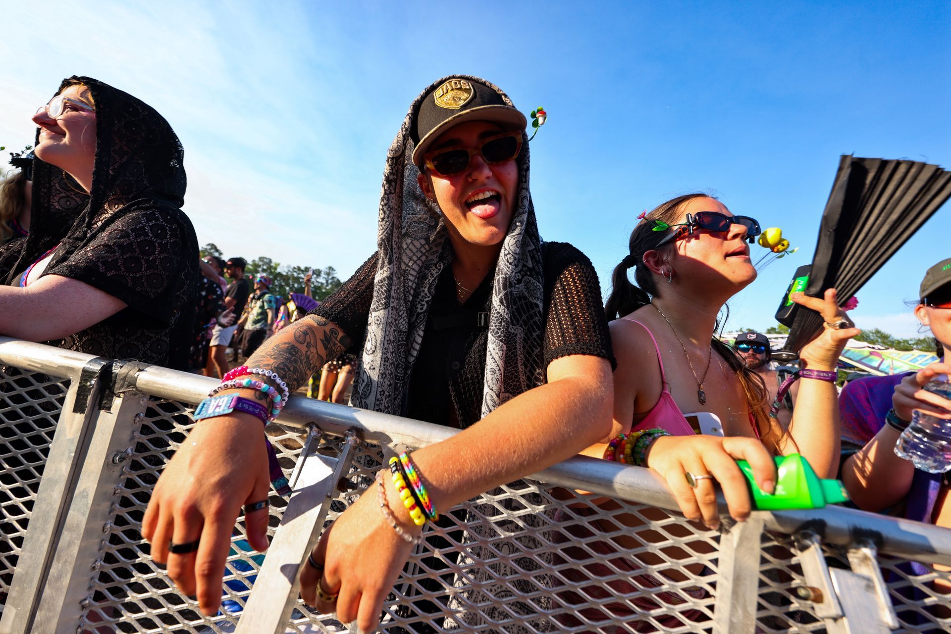 A group of people are sitting behind a metal fence at a concert.