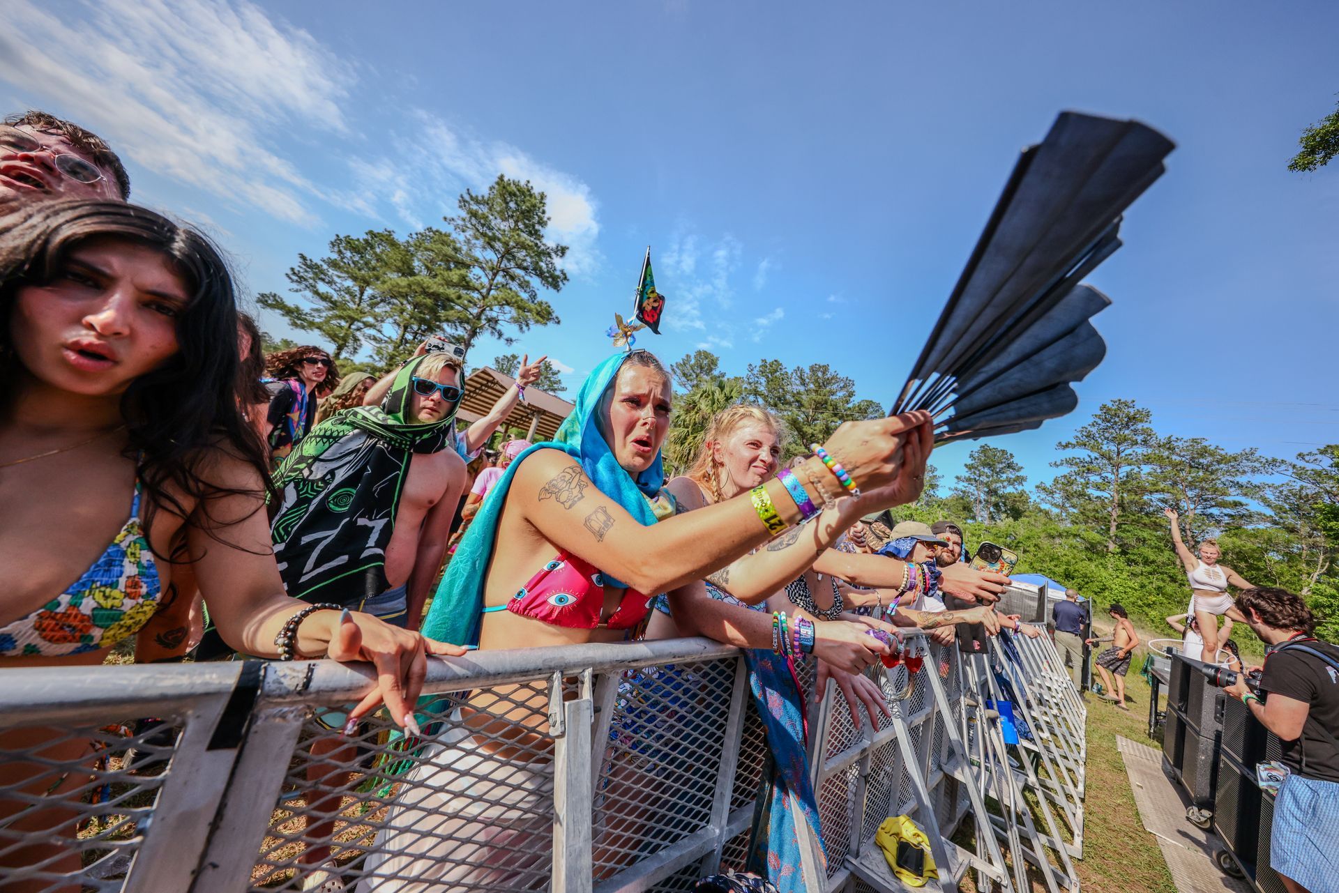 A woman in a bikini is holding a fan in front of a crowd of people.