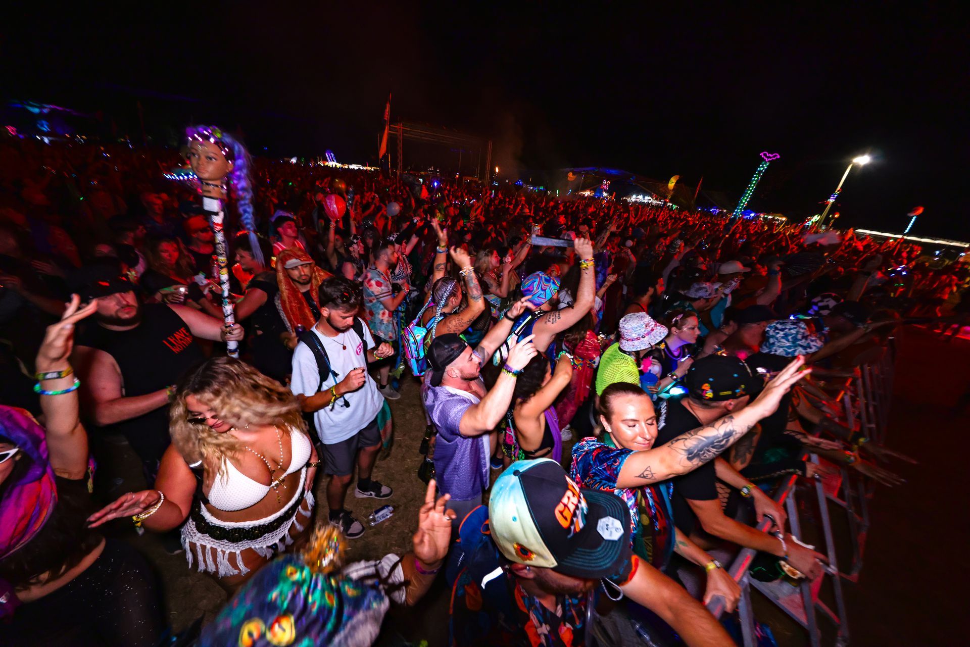 A crowd of people are dancing at a music festival at night.