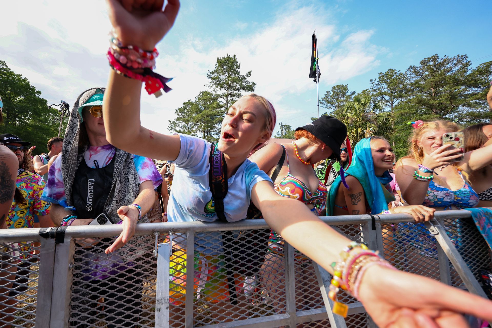 A group of people are standing behind a fence at a music festival.