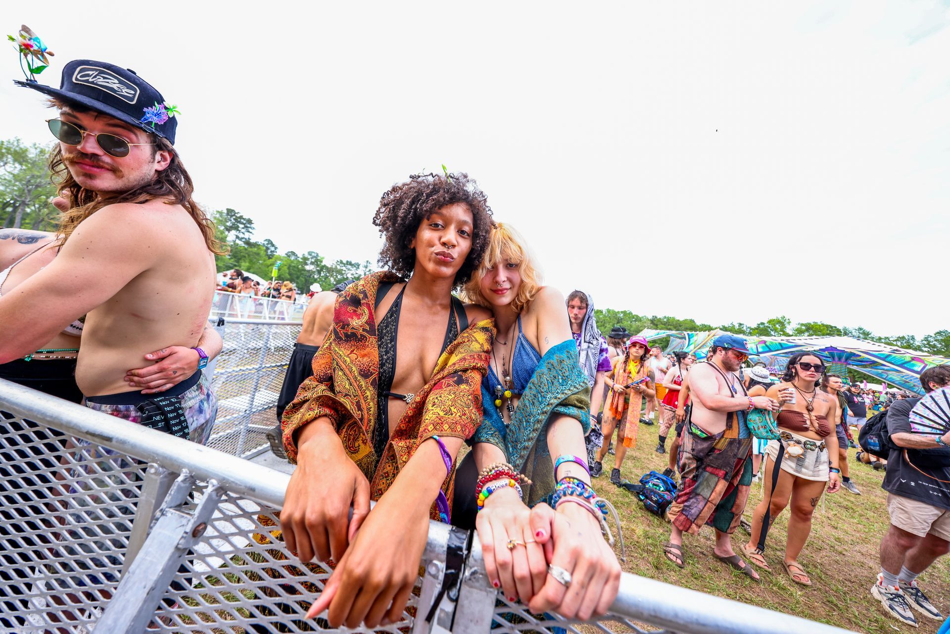 A group of people are standing behind a metal fence at a music festival.