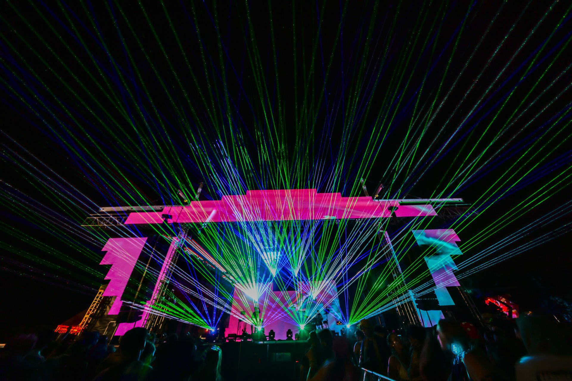 A crowd of people are watching a concert with a lot of lights on the stage.