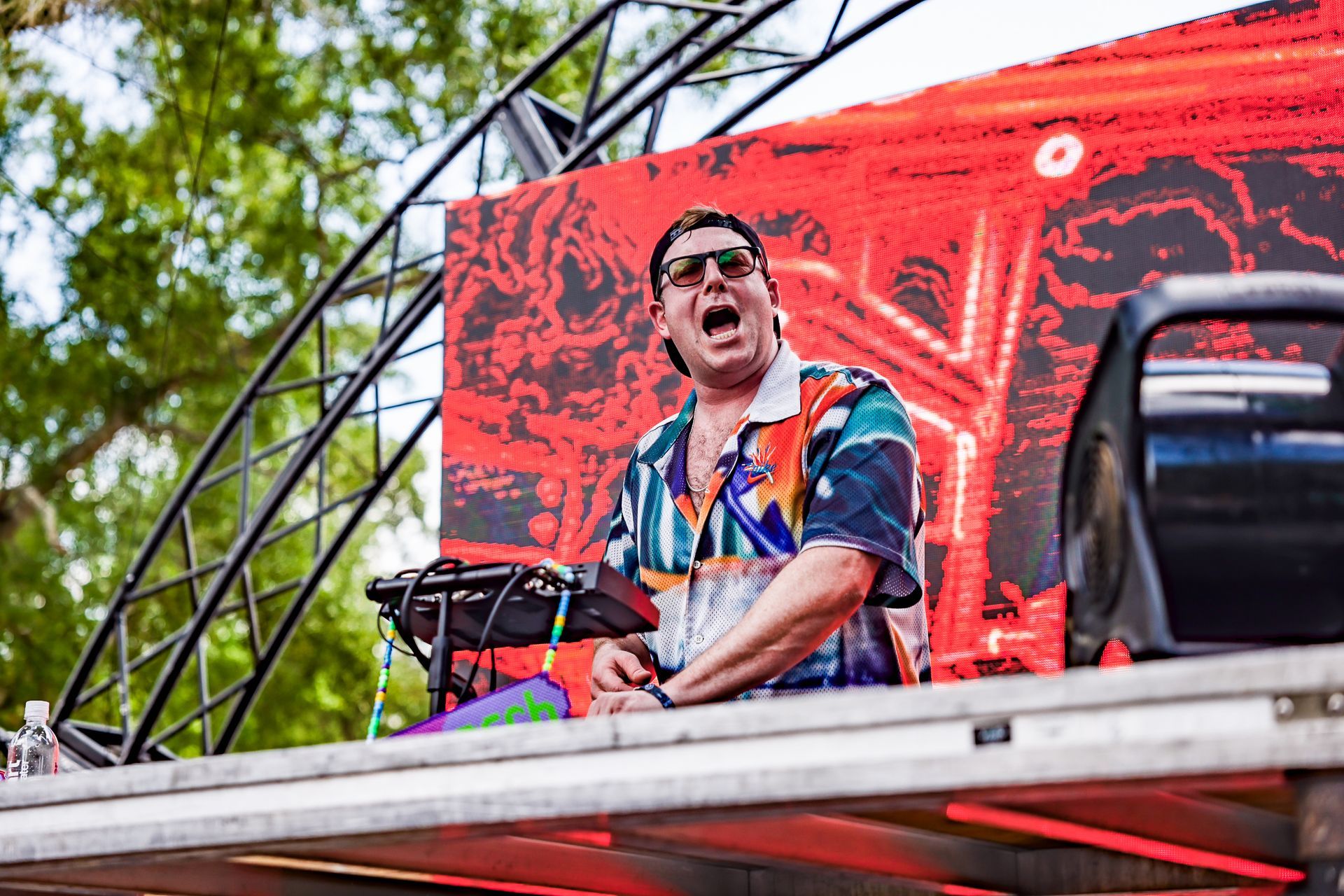 A man is sitting on a stage playing a dj set.