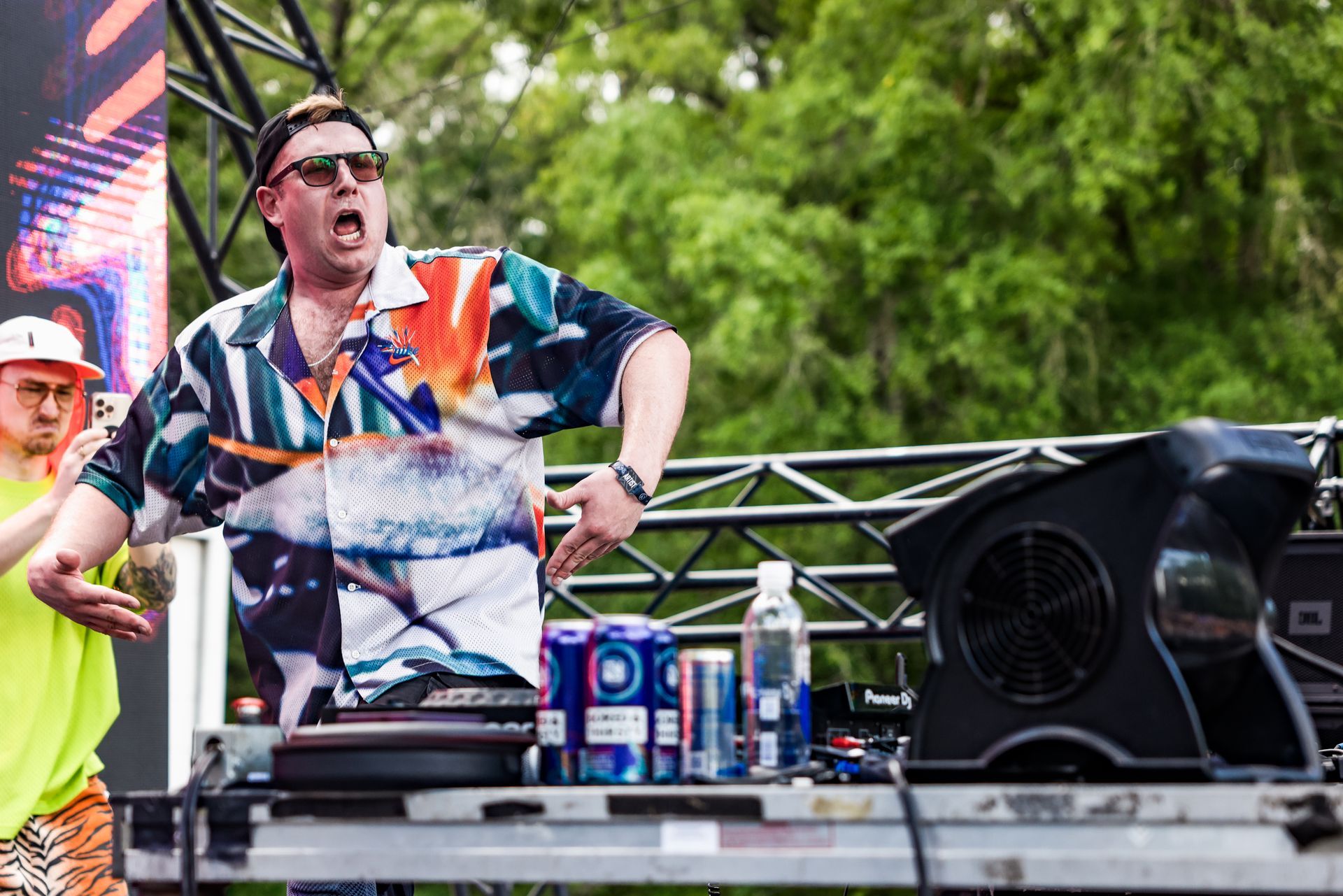 A man is standing in front of a dj booth at a concert.