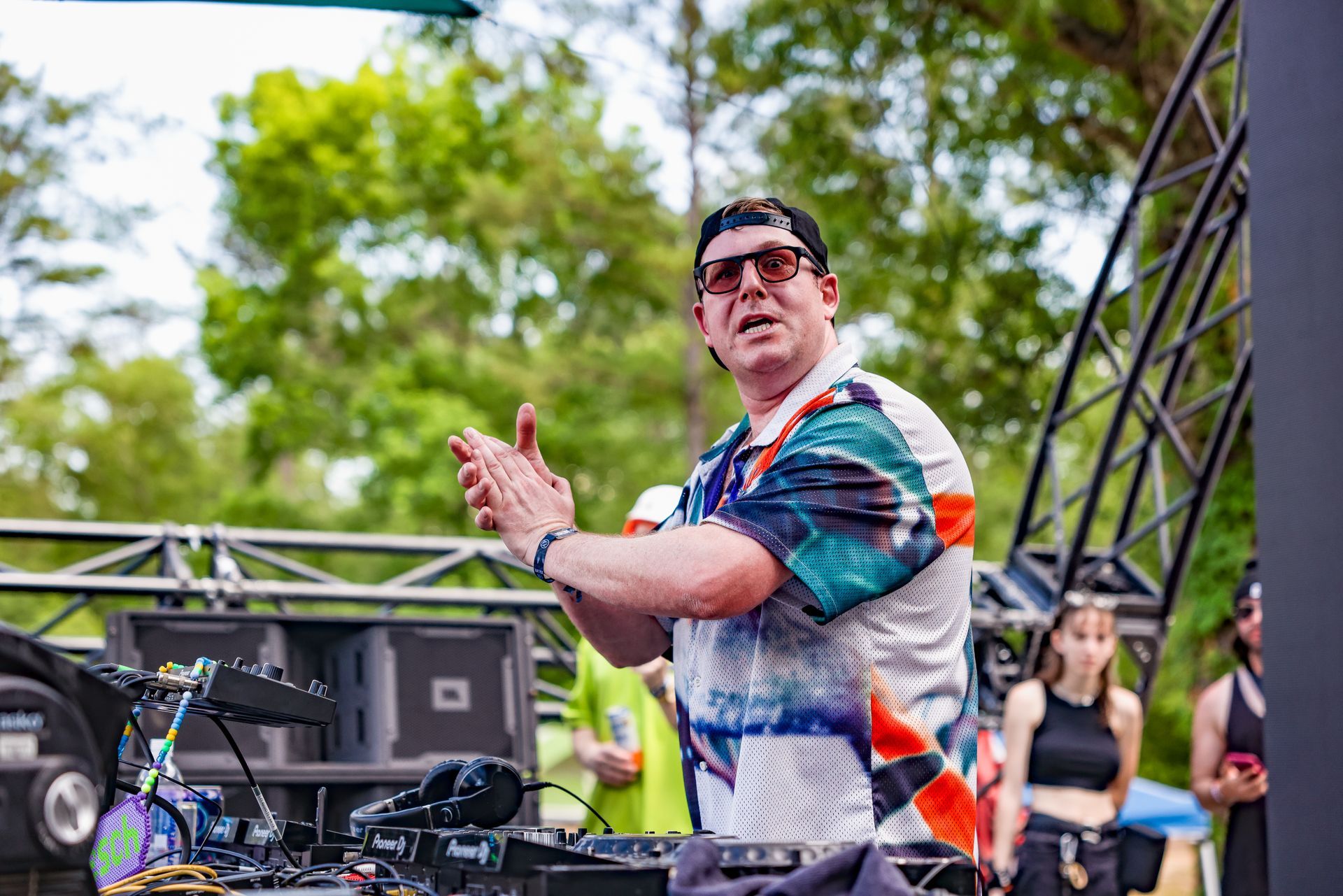 A man is standing in front of a dj mixer on a stage.