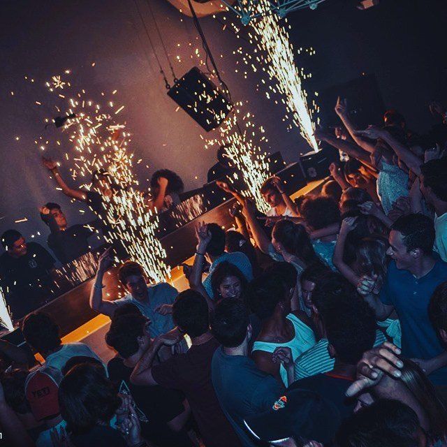 A crowd of people at a party with sparklers coming out of the ceiling
