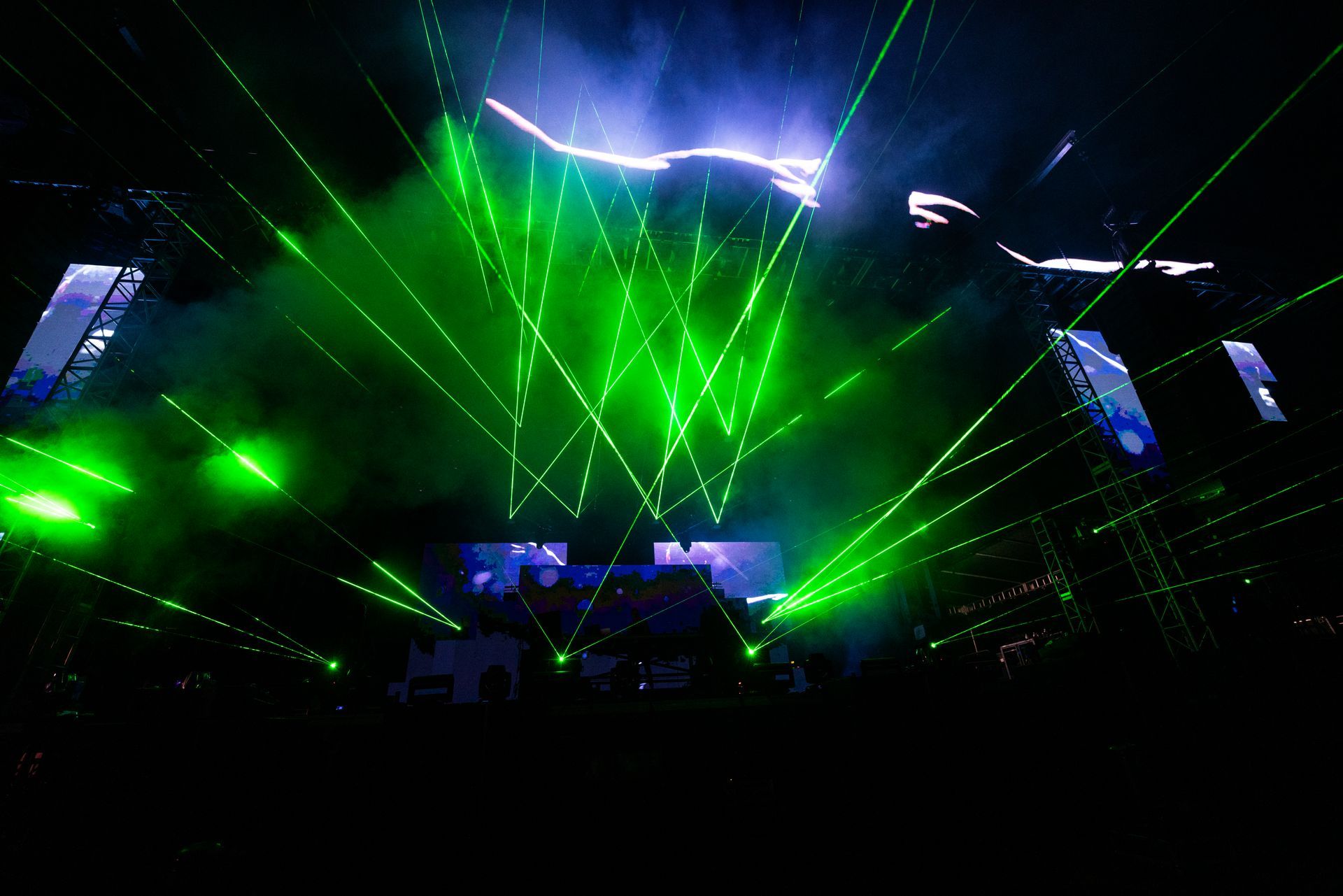 A concert with a lot of green lights coming out of the ceiling.