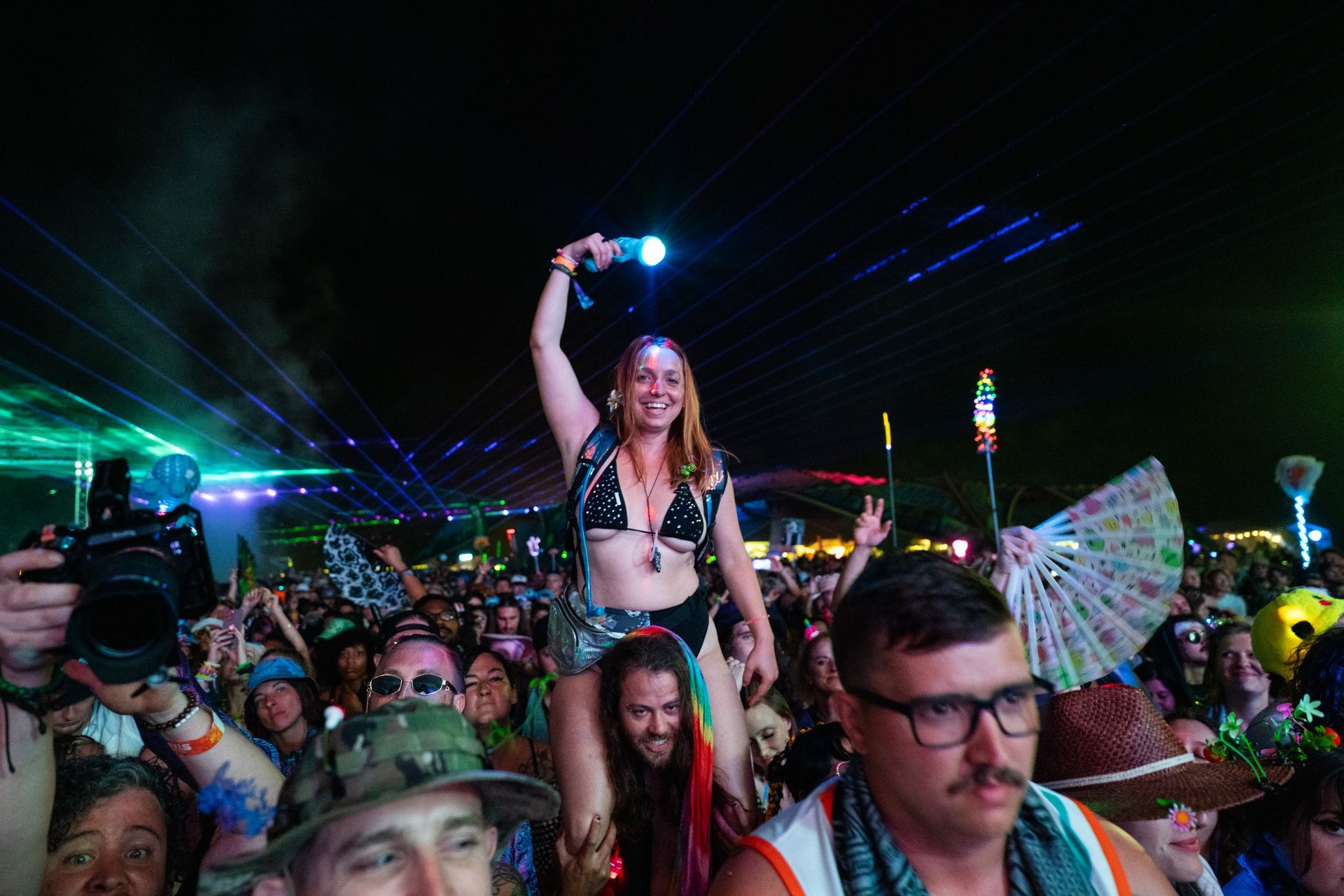 A woman is riding on the shoulders of a man at a concert.