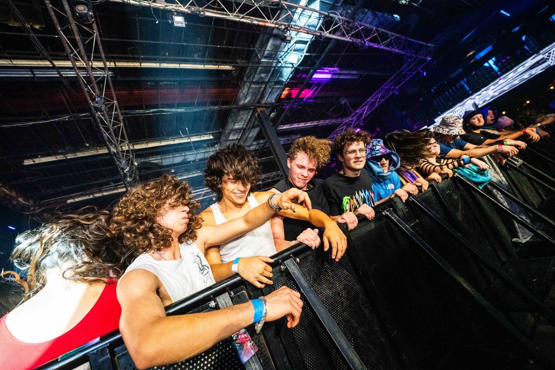 A group of people are standing behind a fence at a concert.