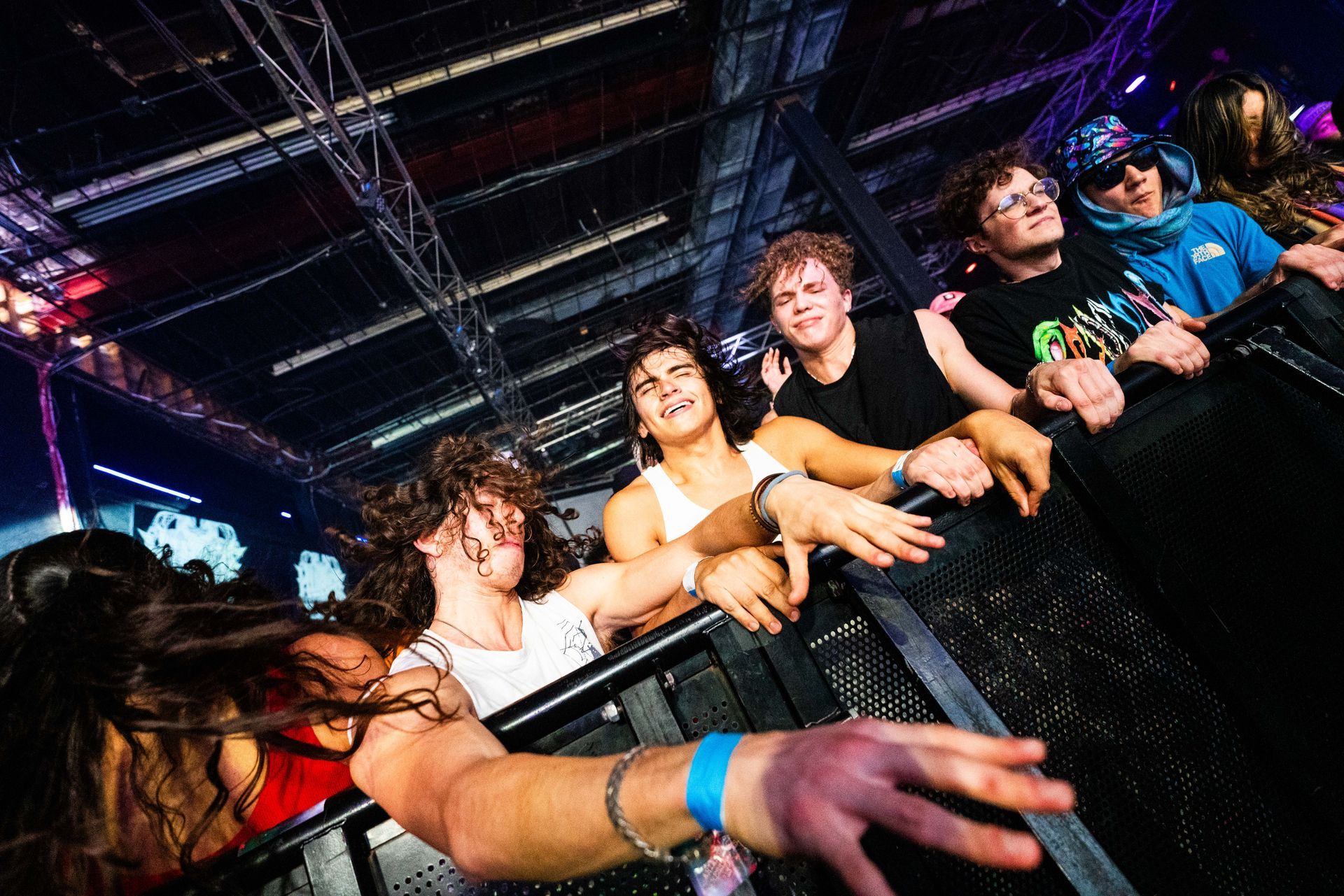 A group of people are standing behind a fence at a concert.