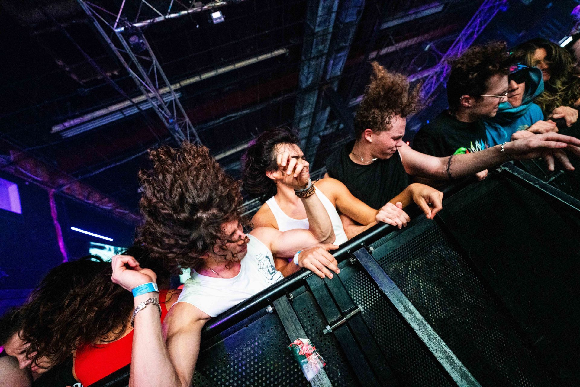 A group of people are standing behind a fence at a concert.