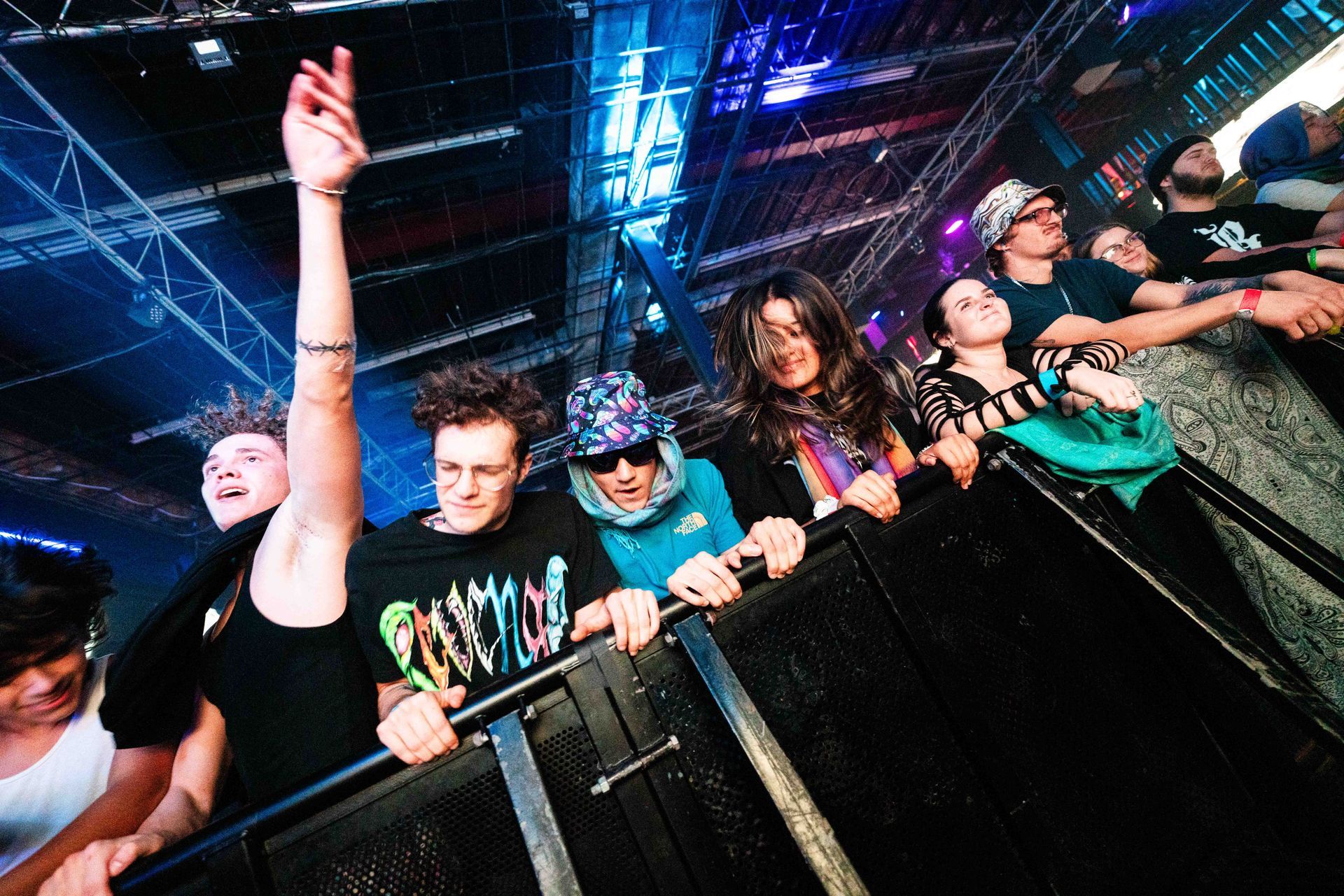 A group of people are standing behind a fence at a concert.