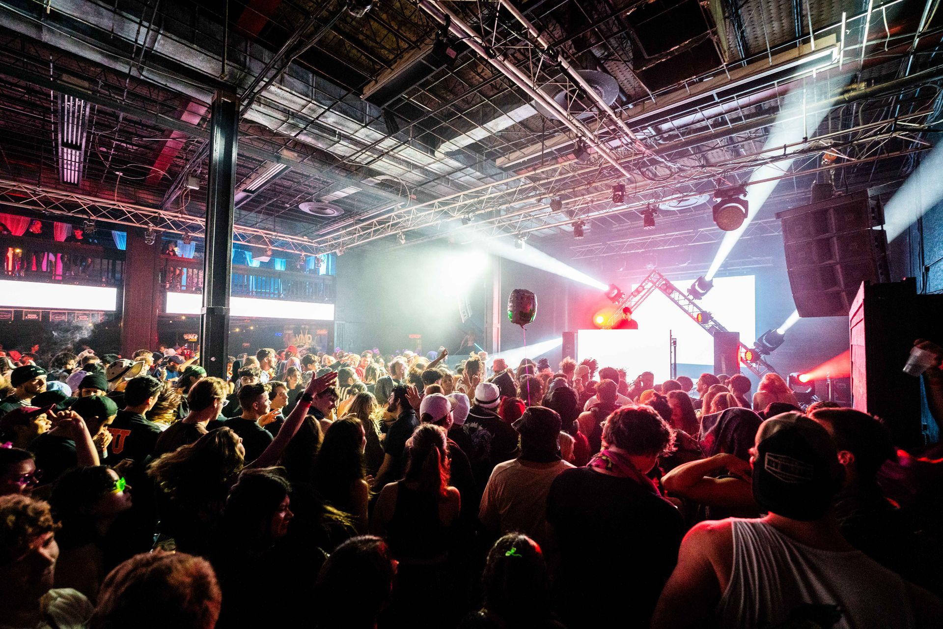 A crowd of people are gathered in a large room at a concert.