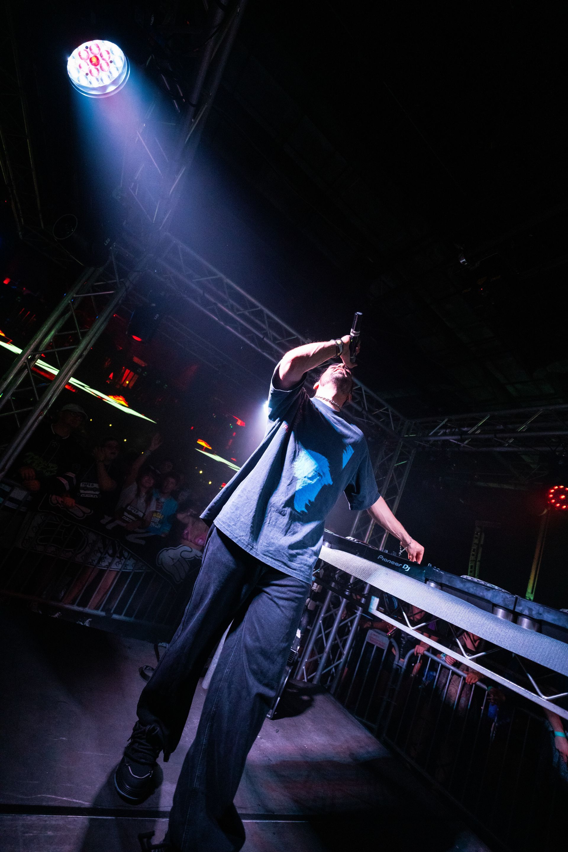 A man is singing into a microphone on a stage in a dark room.