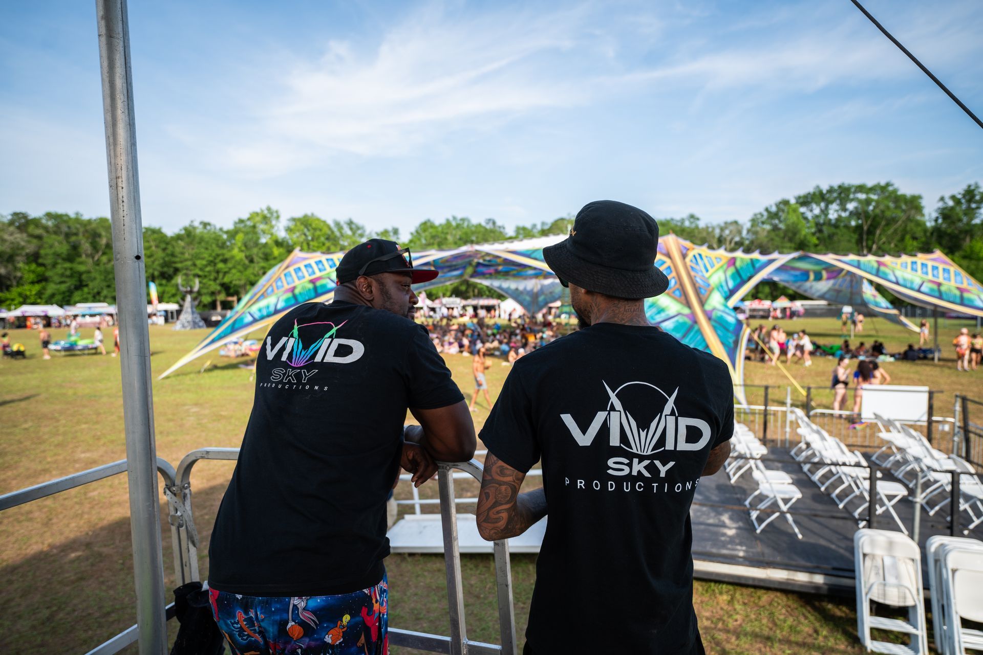 Two men wearing vivid sky shirts are standing next to each other in a field.