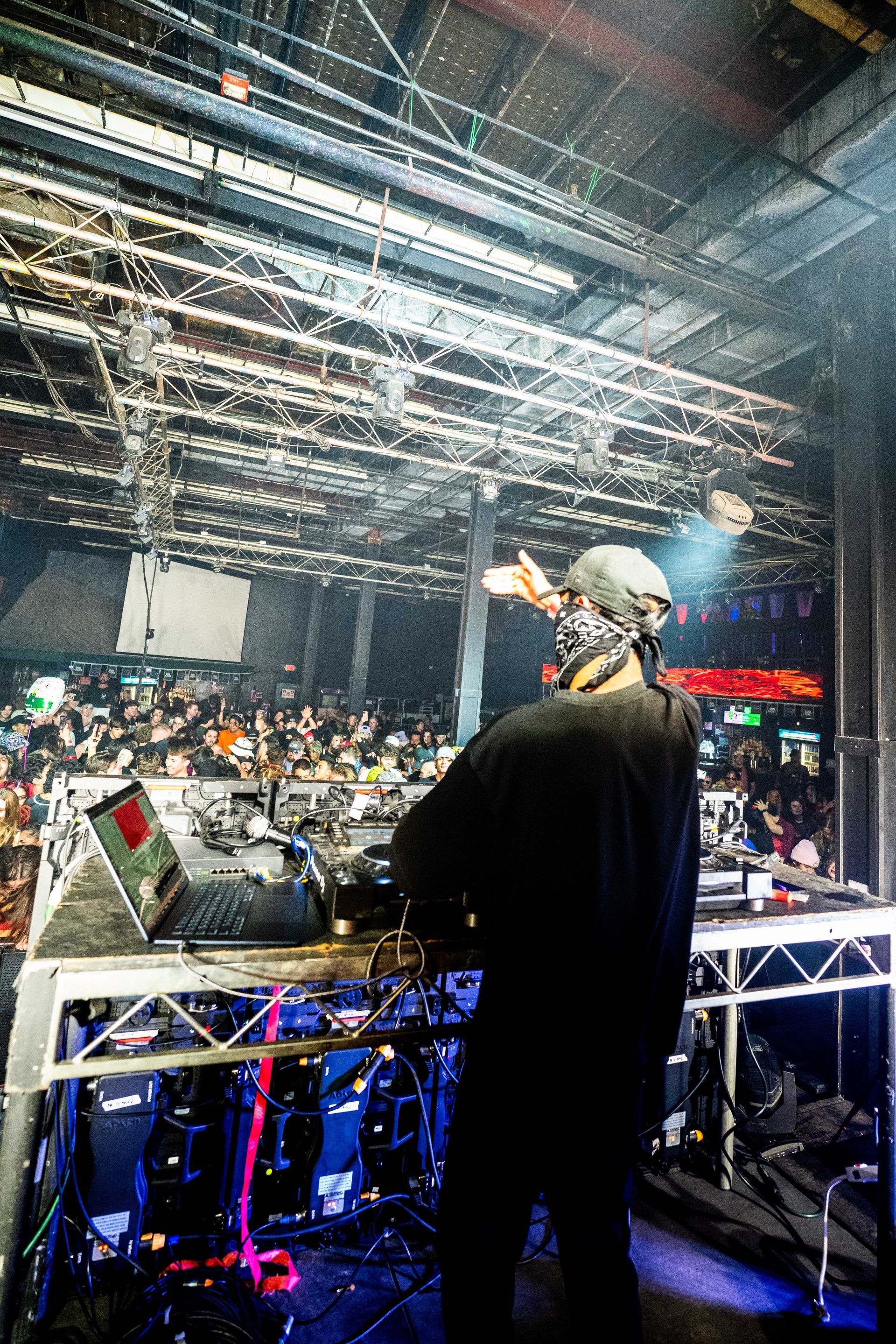A dj is playing music on a stage in front of a crowd.